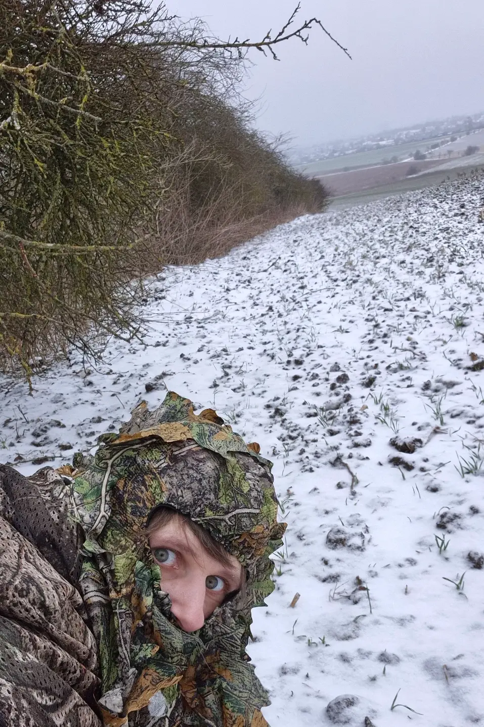 Fotografin liegt im Winter gut getarnt am Feldrand für die Rehfotografie